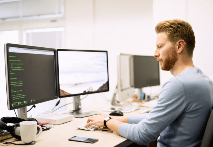 Man with a beard typing a text on the screen in front of him